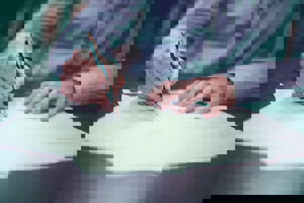 person using pen to write on paper