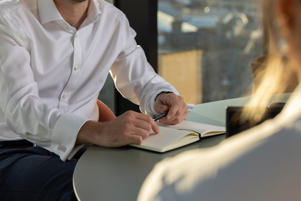 Professional meeting discussing debt recovery strategy, with notes being taken during a client discussion.